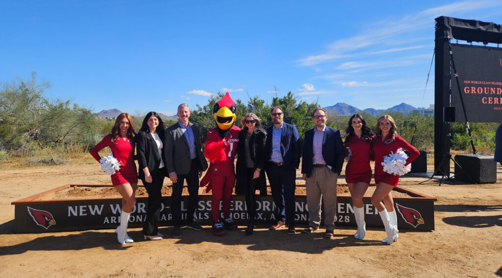 Arizona Cardinals representatives, team mascot, and cheerleaders pose at the groundbreaking site for the new headquarters and performance center.